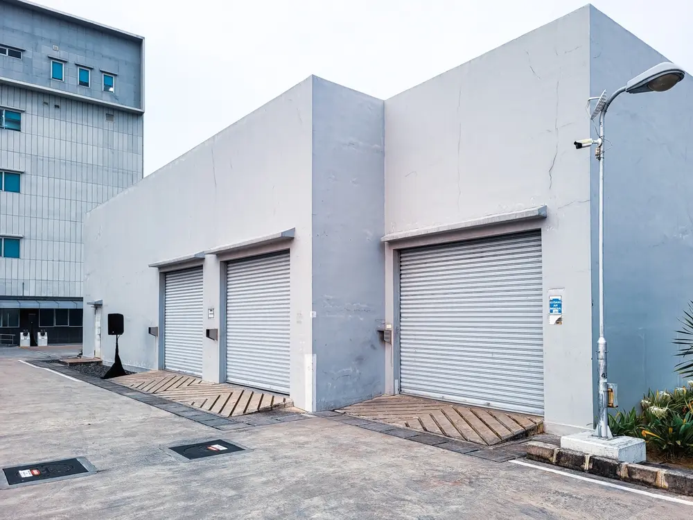 View of several buildings for box-shaped vehicle garages with rolling doors and white walls.