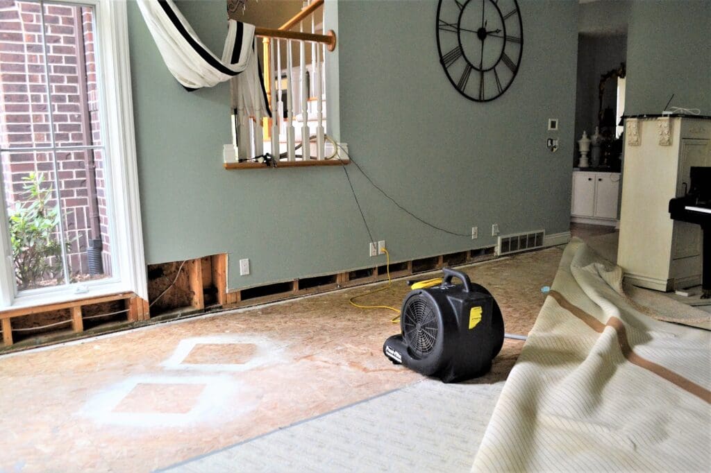 Water damaged home with a fan being used to dry wall