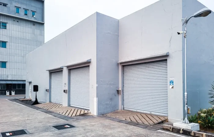 View of several buildings for box-shaped vehicle garages with rolling doors and white walls.